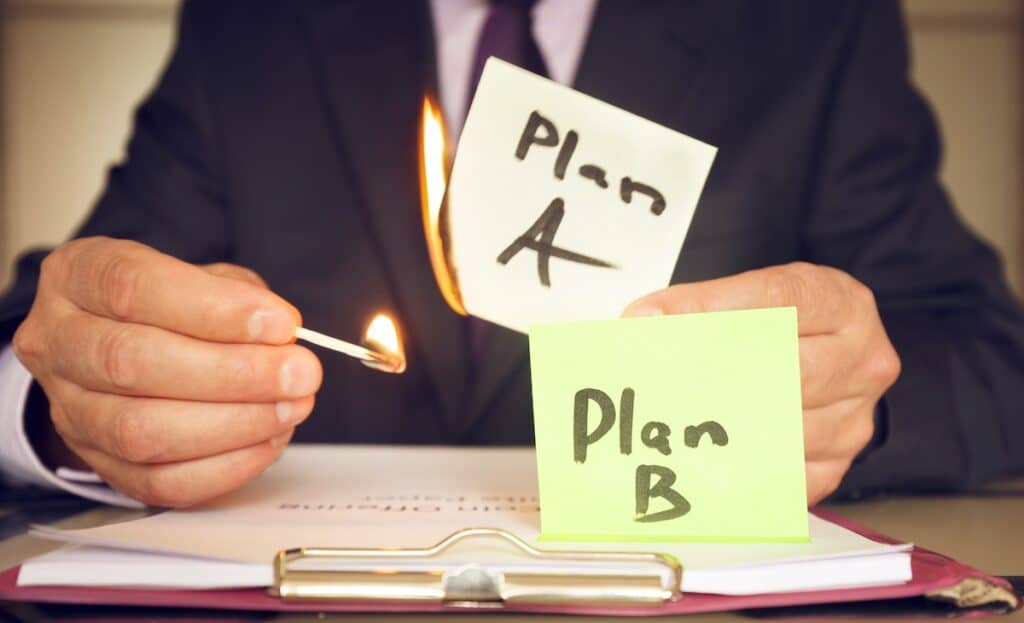 Strategic reboot don't redo reboot your plans - Plan B against plan A. A man holds a burning sticker in his hand as a symbol of the fact that the plan has failed and something has gone wrong.