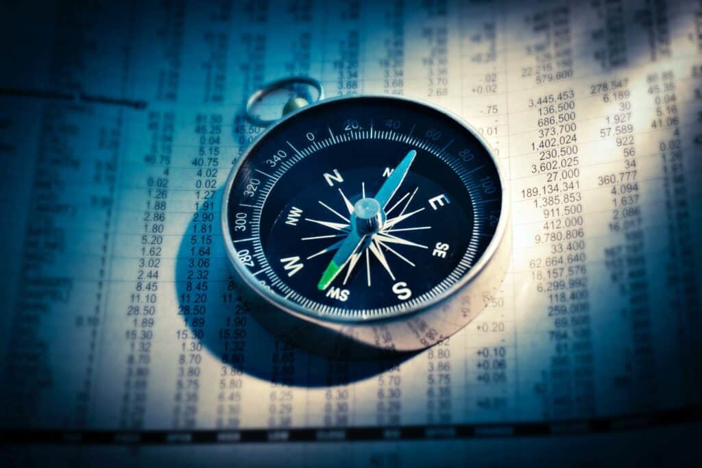 Compass on a paper with stock prices