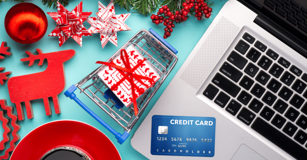 Computer with credit card laying on top surrounded by festive presents
