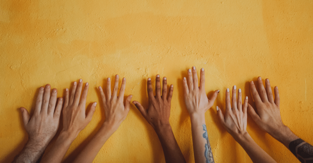 Diverse hands placed on a yellow background