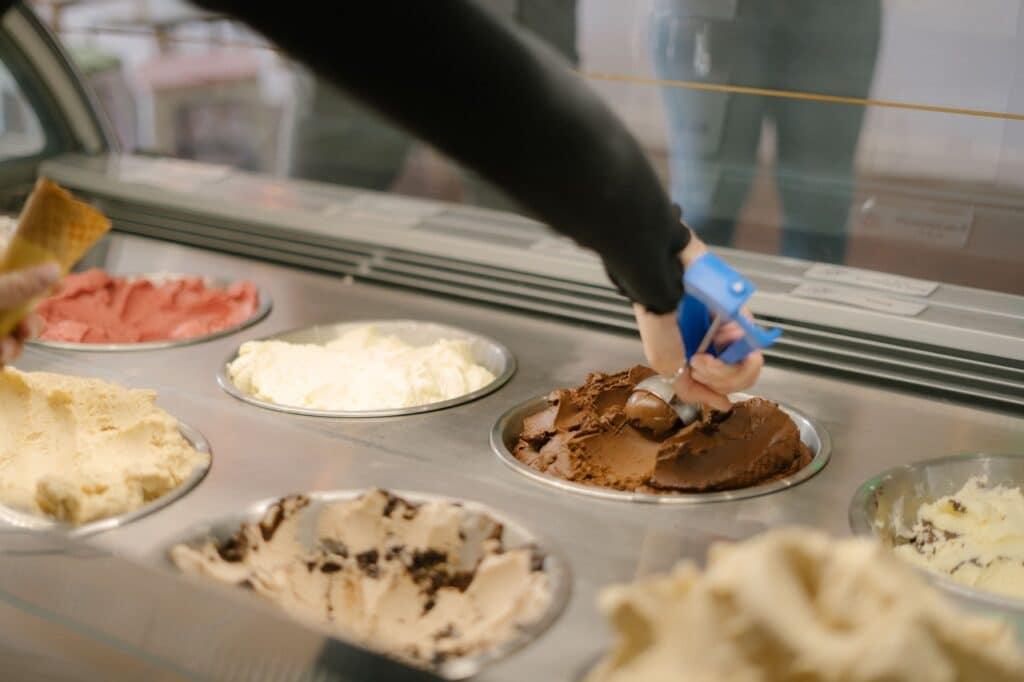 Hand and arm scooping chocolate ice cream in an ice cream parlor